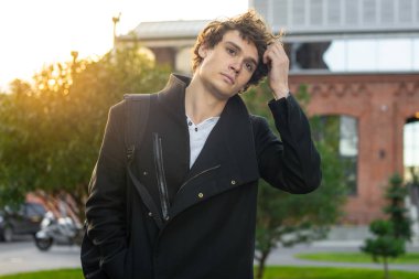 Modern binalar arka plan saçına dokunmak siyah paltolu adam yakın çekim.