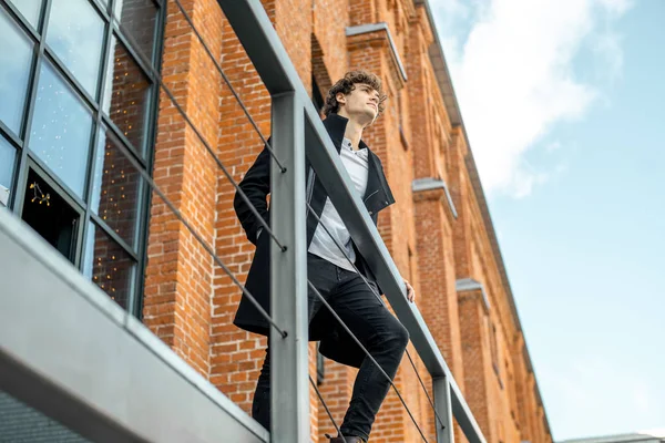 Çekici dalgın adam kırmızı tuğla bina arka plan üzerinde merdiven üzerinde ayakta.