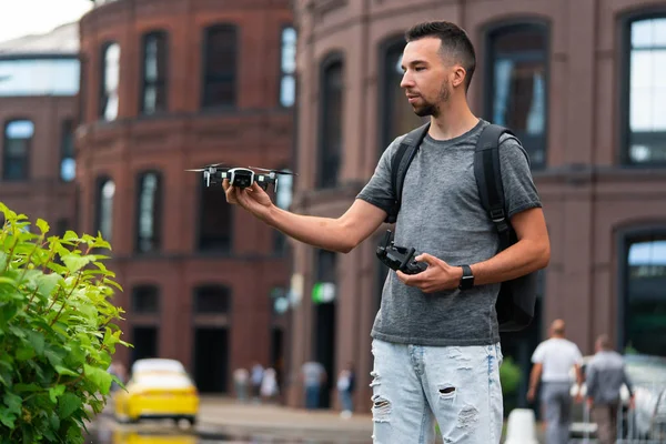 Joven hombre guapo lanzando dron quadcopter en el fondo urbano . — Foto de Stock