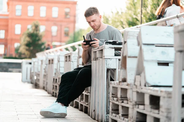 Joven hombre guapo con dron quadcopter controlador de joystick en el fondo urbano . — Foto de Stock