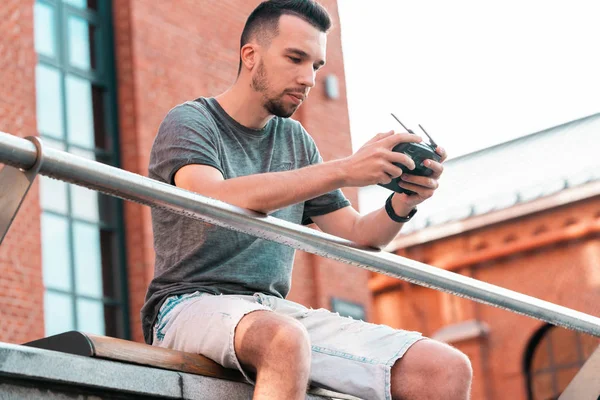 Mladý pohledný muž s trubkovým ovladačem čtyřpákového ovladače na městském pozadí. — Stock fotografie