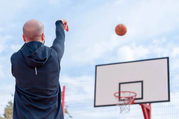 Homme attrayant jouant au basket et plongeant basket-ball dans le cerceau sur le terrain de basket-ball . — Photo