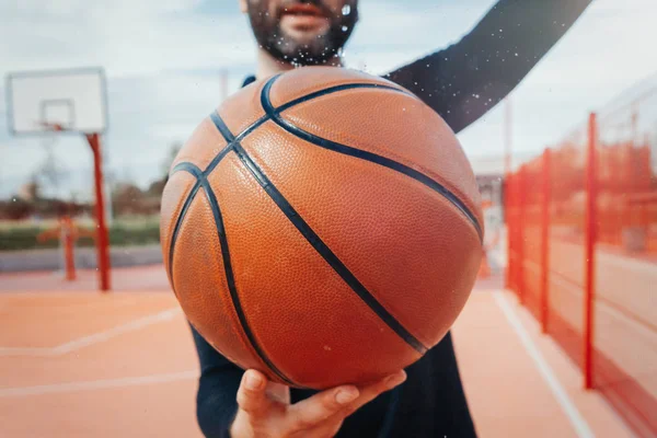 Close up of attractive man holding basket ball. Ball is on focus and foreground. — Stock Photo, Image