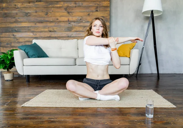 Genç sarışın kadın evde germe yoga egzersizleri yapıyor. Sağlıklı yaşam tarzı.