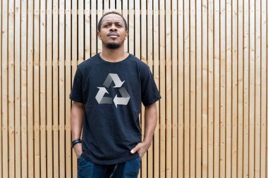 Ahşap arka plan üzerinde geri dönüşüm sembolü ile t-shirt genç çekici adam. Eko sembolü.