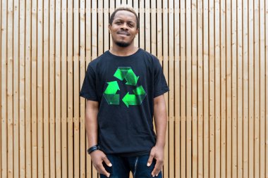 Ahşap arka plan üzerinde geri dönüşüm sembolü ile t-shirt genç çekici adam. Eko sembolü.