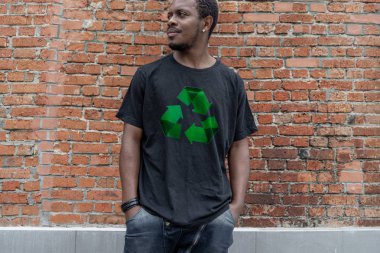 Tuğla arka plan üzerinde geri dönüşüm sembolü ile t-shirt genç çekici adam. Eko sembolü.