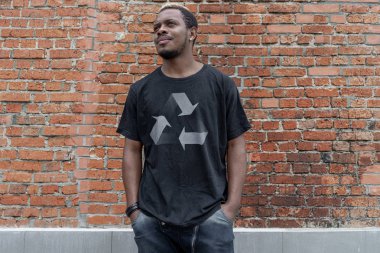 Tuğla arka plan üzerinde geri dönüşüm sembolü ile t-shirt genç çekici adam. Eko sembolü.