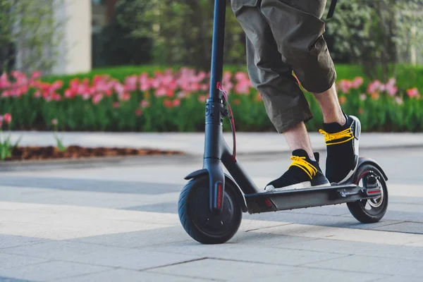 Close up de homem montando scooter de chute elétrico preto na bela paisagem do parque — Fotografia de Stock