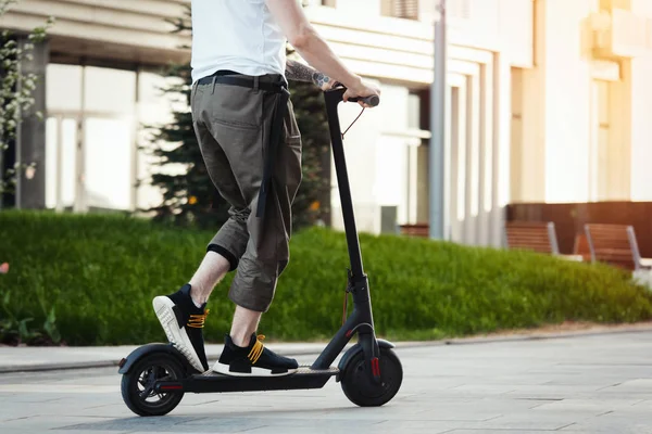 Nahaufnahme eines Mannes auf einem schwarzen Elektro-Tretroller in einer wunderschönen Parklandschaft — Stockfoto