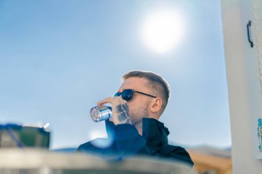 Yakışıklı, düşünceli, stil sahibi adam balkonda oturuyor ve dizüstü bilgisayarla çalışıyor..