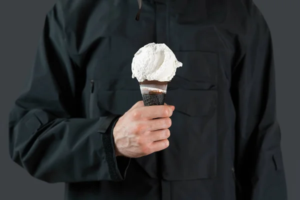 Close up of man in black minimalistic raincoat holding ice cream in black waffle cone. Minimalism concept. — Stock Photo, Image