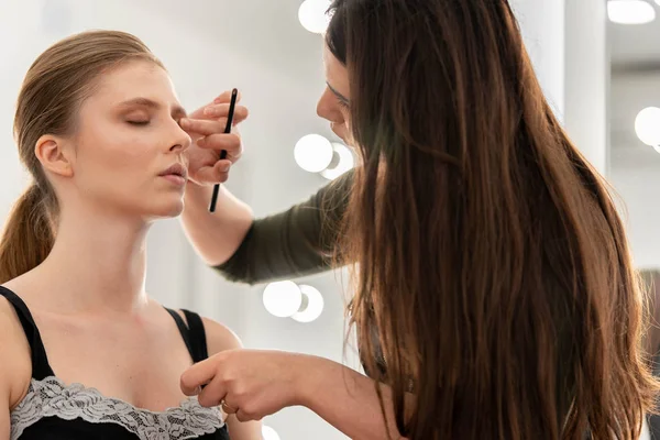 Autor umělce aplikuje stíny očí. Ruka pro make-up, malování modelových očí — Stock fotografie