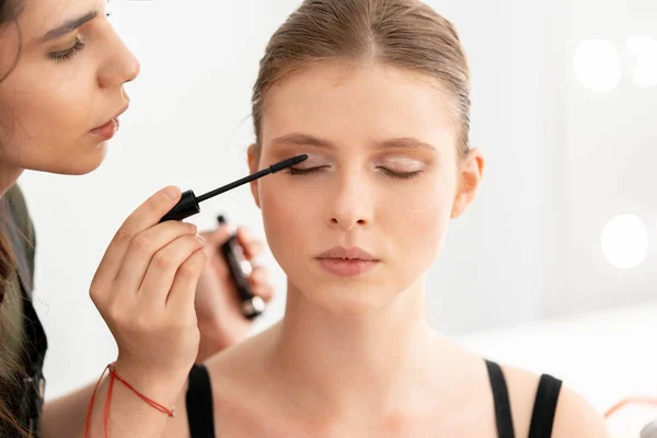 Make up artist applies mascara. Hand of make-up master, painting model eyes — Stock Photo, Image