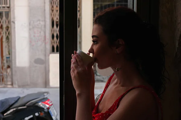 Bella giovane donna godendo tazza di caffè e guardando la strada della città vecchia europea al mattino tempo . — Foto Stock