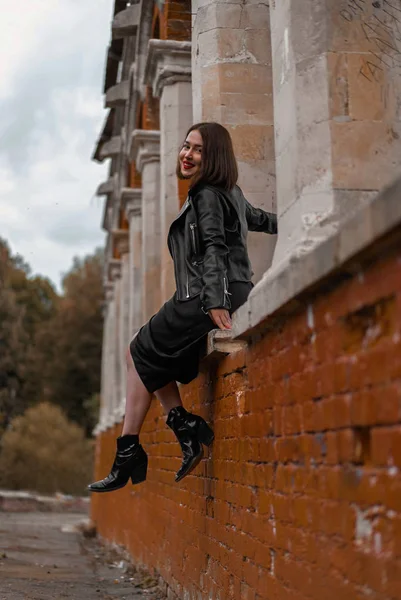 Giovane bella donna bruna in abito nero in posa presso antiche rovine . — Foto Stock