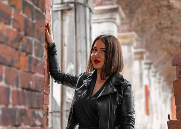 Giovane bella donna bruna in abito nero in posa presso antiche rovine . — Foto Stock