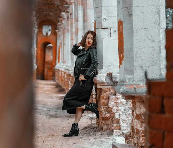 Jeune belle femme brune en robe noire posant sur des ruines anciennes . — Photo
