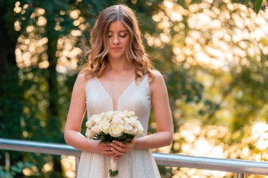 Gülümseyen Gelin parkta açık havada düğün günü damat önünde elinde Düğün buketi tutarak