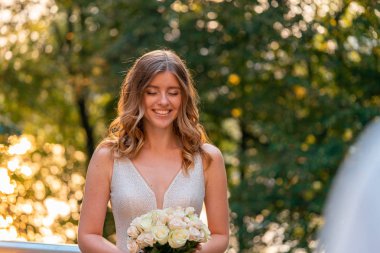 Gülümseyen Gelin parkta açık havada düğün günü damat önünde elinde Düğün buketi tutarak