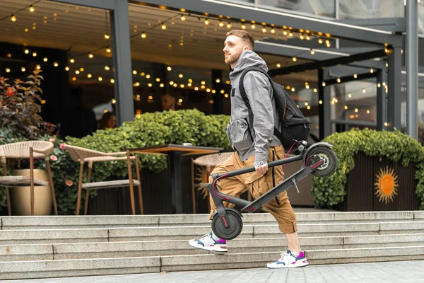 Man håller elektrisk Spark skoter medan man går på en promenad på gatan eller på Café. — Stockfoto