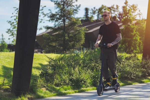 Привабливий чоловік їде електричним скутером на красивому парковому ландшафті . — стокове фото