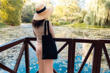 Parkta siyah boş çantalı bir kadın. Boş alan için yer. Kopya alanı. Çevre dostu.