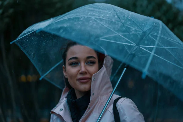 Hezká dívka držící deštník a procházející se v deštivém podzimním dni. fotografie vypadá jako snímek filmu nebo filmový snímek ve studených barvách — Stock fotografie