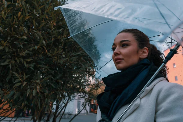 Pretty girl holding umbrella and strolling on rainy autumn day. photo looks like film frame or movie screenshot. processed in cold colors — 图库照片