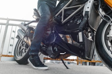 Motosikletin üzerinde oturan motosikletlinin yakın plan fotoğrafı..