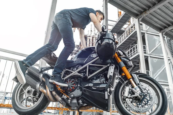 Motociclista guapo sentado en motocicleta en el fondo urbano en el aparcamiento . —  Fotos de Stock