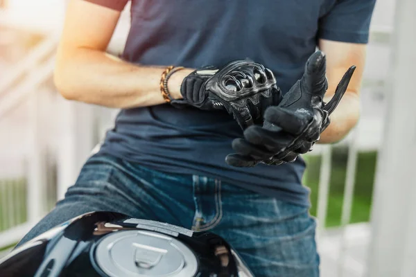Close up of biker putting on black gloves and sitting on motorcycle. — Stock Photo, Image