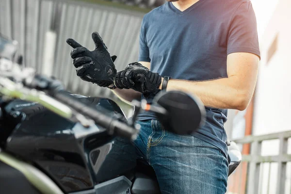 Close up de motociclista vestindo luvas pretas e sentado em moto . — Fotografia de Stock