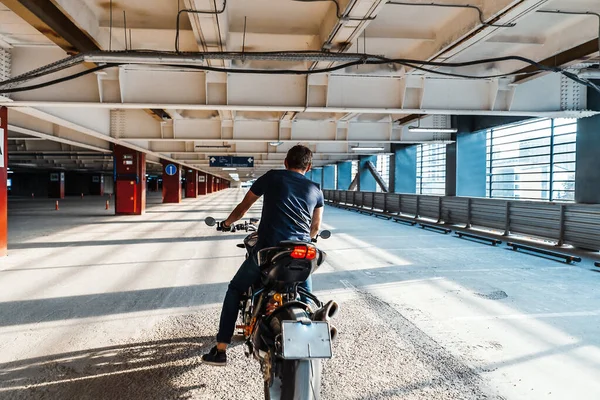 Plan distante de motociclista a caballo en el aparcamiento. Fondo urbano . —  Fotos de Stock