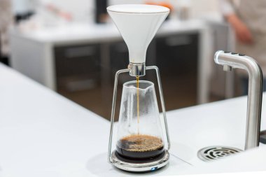 process of preparation black coffee in chemex pour over coffee maker in bright modern cafe. Alternative ways of brewing coffee. clipart