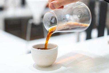 Parlak modern kafede kahve makinesinin üzerine siyah kahve dökülüyor. Kahve yapmak için alternatif yollar..