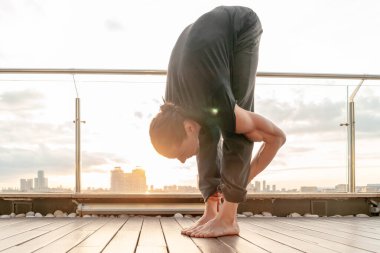 Çekici atletik adam iş merkezinde yoga yapıyor. Gökdelenden güzel bir manzarası var..