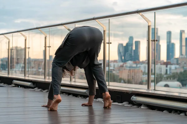 Homme athlétique attrayant pratiquant le yoga dans un centre d'affaires avec une belle vue sur une ville depuis le gratte-ciel . — Photo