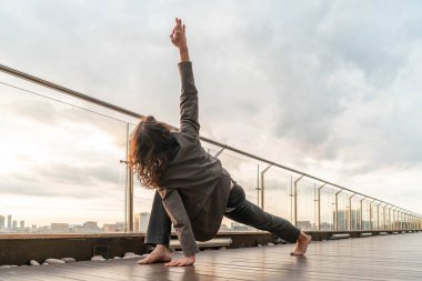 Çekici atletik adam iş merkezinde yoga yapıyor. Gökdelenden güzel bir manzarası var..