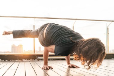 Atletik Sporcu, gün batımıyla birlikte şehir arka planında ikiye ayrılıp, esneme hareketleri yapıyor. Öz 'le uyum içinde yaşamak. İçten içe mutlu. Asana. Gürültü ve Tahıllı Görüntü