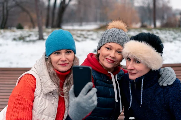 Mujeres maduras sonriendo y haciendo selfie en el parque después de un entrenamiento activo al aire libre. Amigos de mediana edad pasan tiempo juntos — Foto de Stock