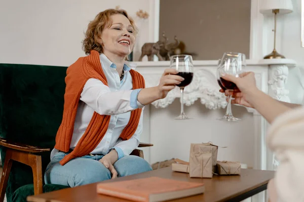 Viejos amigos se reunieron en la elegante sala de estar y beber vino. Happy Smiling Senior Blonde Woman Giving A Toast About Woman Friendship (en inglés). Envejecimiento natural — Foto de Stock