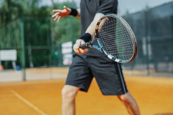 Gros plan de l'homme jouant au tennis à la cour et battant la balle avec une raquette. Joueur frappe balle avec raquette tout en jouant match — Photo