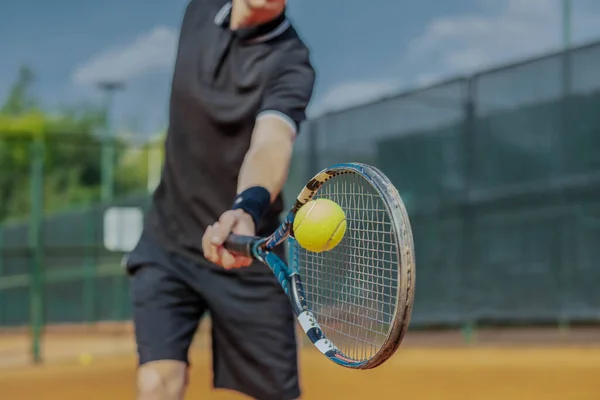 Gros plan de l'homme jouant au tennis à la cour et battant la balle avec une raquette. Joueur frappe balle avec raquette tout en jouant match — Photo