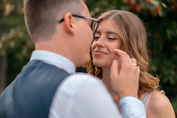 Gros plan du visage de la mariée et de la main du marié touchant son visage avec tendresse. Femme regardant mari avec amour et adoration. Cérémonie de mariage au parc — Photo