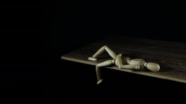 Stopmotion houten figuur dummy treuzelt in studio op zwarte achtergrond leggen en benen zwaaien — Stockvideo