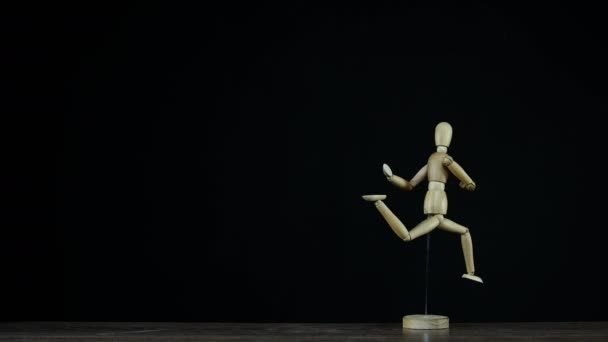 Stopmotion fonctionnement figurine en bois mannequin en studio sur fond noir tourne avec mouvement congelé pour les titres 