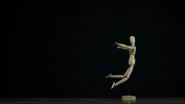 Stopmotion faller trä Figur dummy i studio på svart bakgrund roterande för titlar — Stockvideo