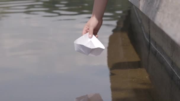 A childs hand launches a paper boat to the river in summer in slow motion — Stock Video