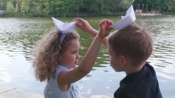 Children play with a paper boats near the river in slow motion — Stock Video